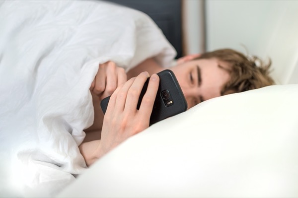 ベッドでスマートフォンを見ている画像